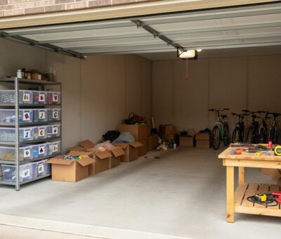 Wide view of a garage workspace with a pegboard wall, shelving units, and clear bins holding neatly sorted tools.